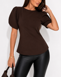 Woman wearing a brown top and black pants against a white background